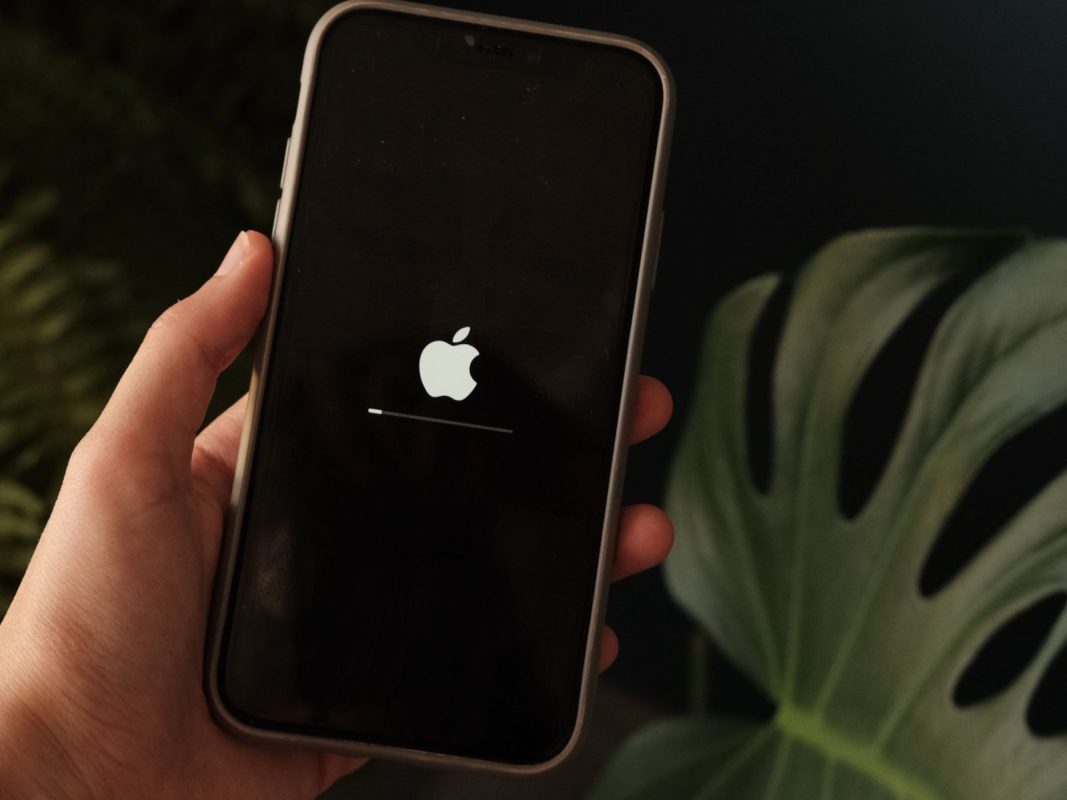 Рука держит iPhone с экраном обновления iOS 26.6