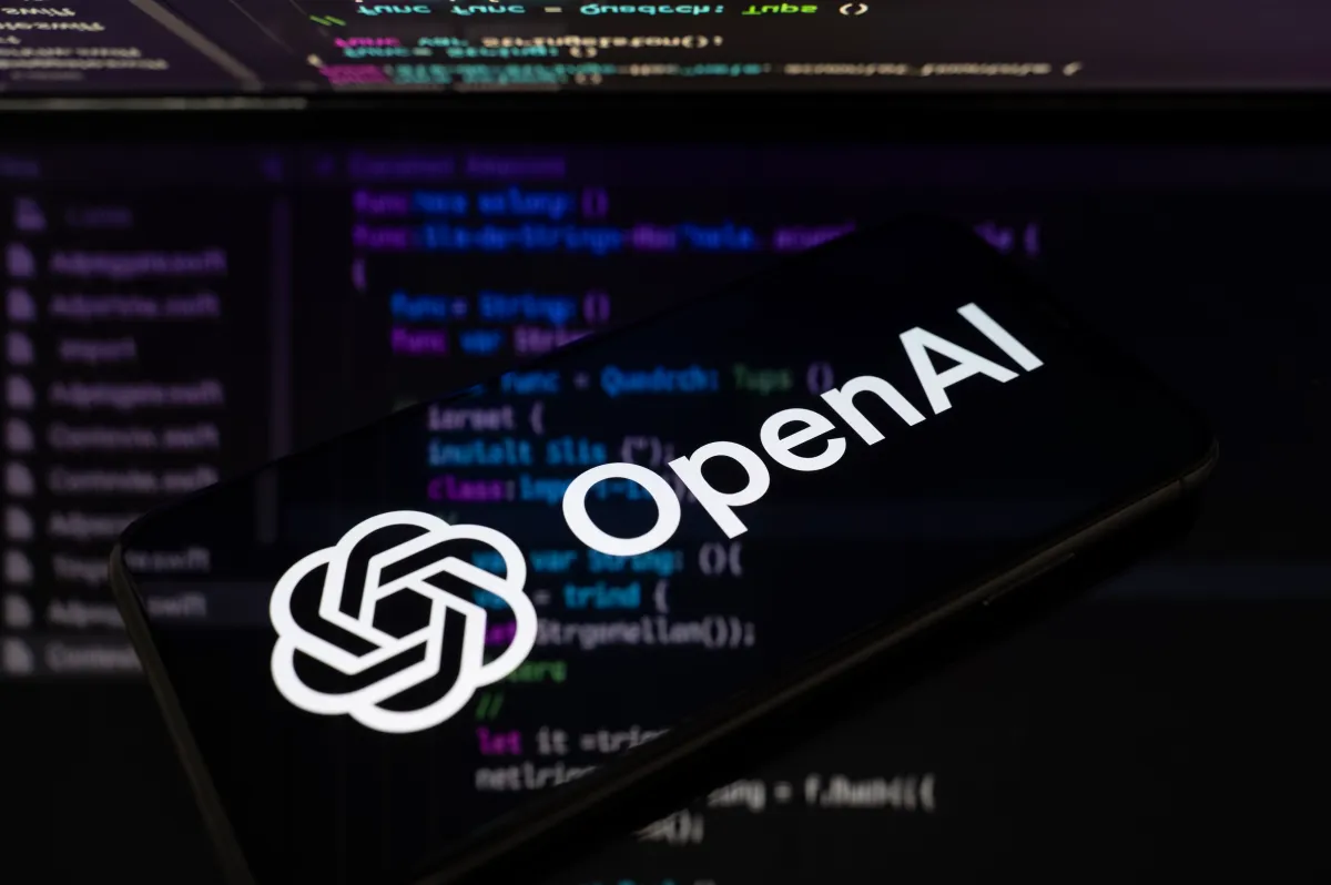 Логотип OpenAI на экране смартфона на фоне кода