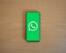 Смартфон на деревянном столе с экраном запуска WhatsApp и логотипом