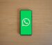 Смартфон на деревянном столе с экраном запуска WhatsApp и логотипом