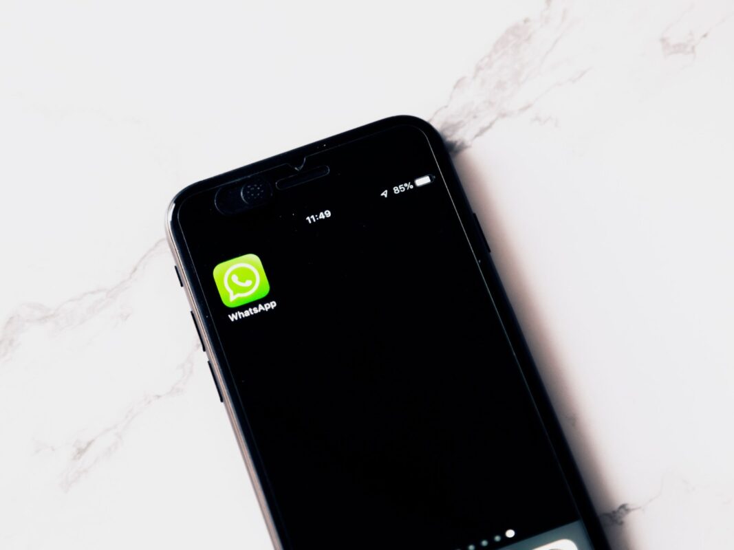 Смартфон на белом столе с открытым приложением WhatsApp